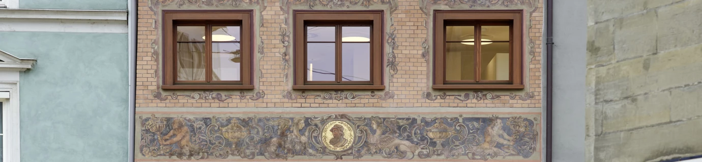 Geschäftshaus Huber mit Ziegelmauerwerk, verzierten Fenstern und drei Dachgauben an der Rathausstraße. Im Erdgeschoss Uhren- und Schmuckgeschäft.
