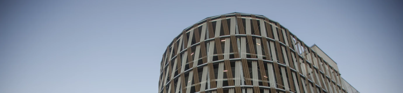 Gerundete Hochgarage am Wiener Hauptbahnhof mit einem Fernmeldeturm und Bahnsteigen im Hintergrund (Wien).