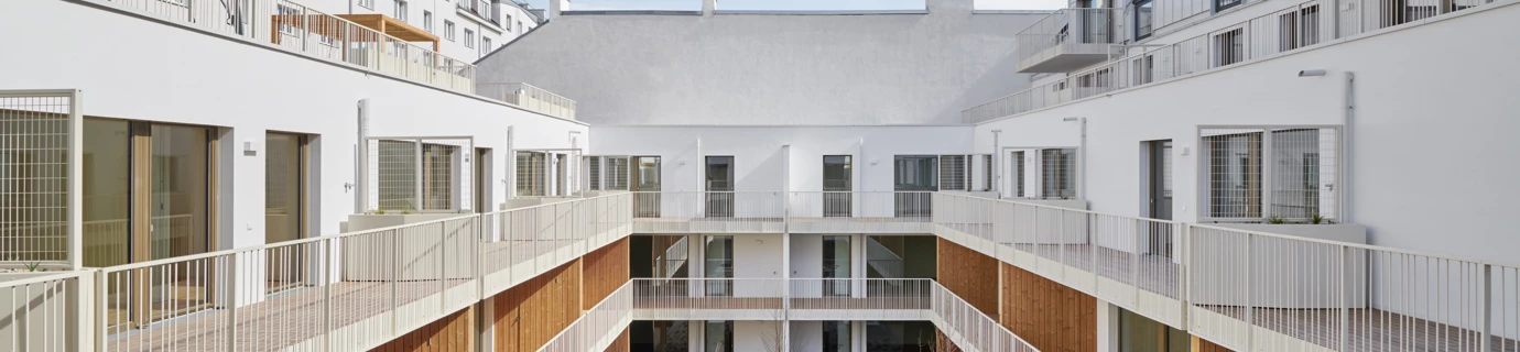 Innenhof eines modernen Wohngebäudes in der Apollogasse in Wien mit Holzterrassen, Balkonen und Kiesbeeten