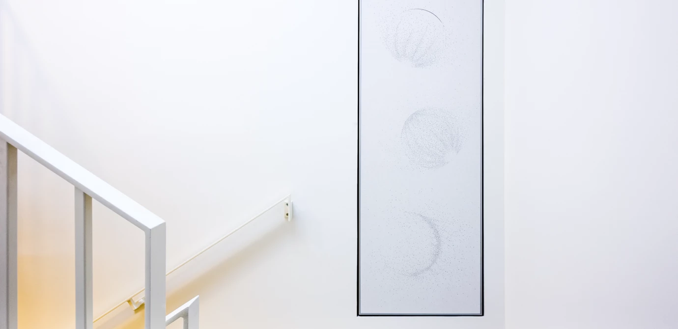 Abstrakte Kunstinstallation mit drei Kreisen an einer weißen Wand neben einem Treppenaufgang (Wohnanlage, Eicheleweg)