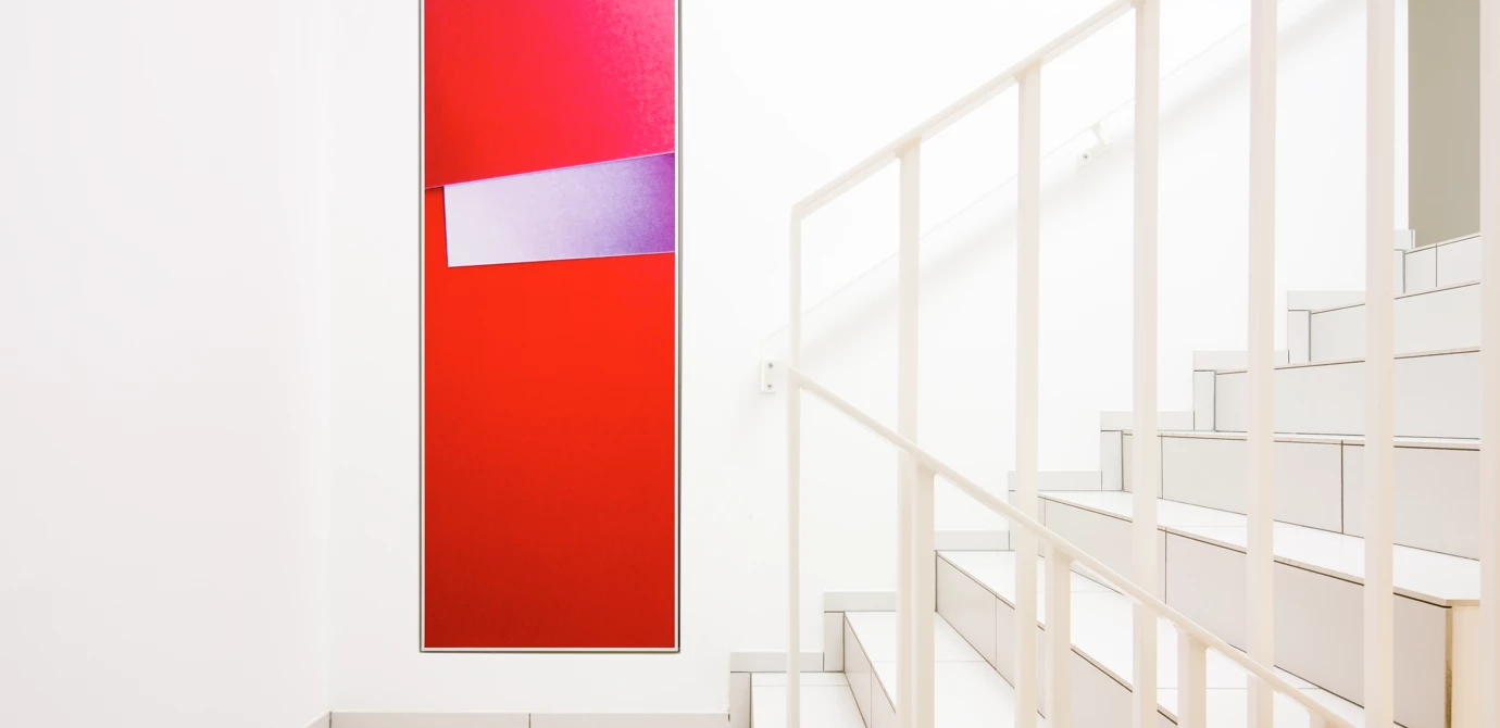 Rotes abstraktes Kunstwerk mit einem lila Streifen an einer weißen Wand neben einer weißen Treppe mit Geländer (Wohnanlage, Eicheleweg).