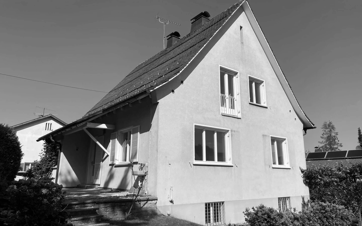 Einfamilienhaus in Dornbirn vor der Generalsanierung in Schwarz-Weiß-Ansicht mit altem Putz und Fenstern.