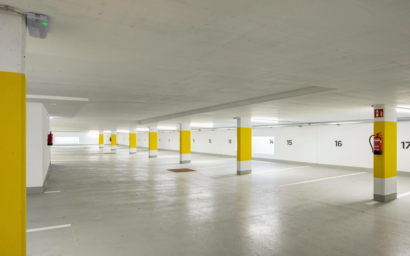 Eine saubere, moderne Tiefgarage mit gelb gestrichenen Säulen und Parkplatznummern von 8 bis 17, Bludenz (Zürcherstraße, Wohnanlage)