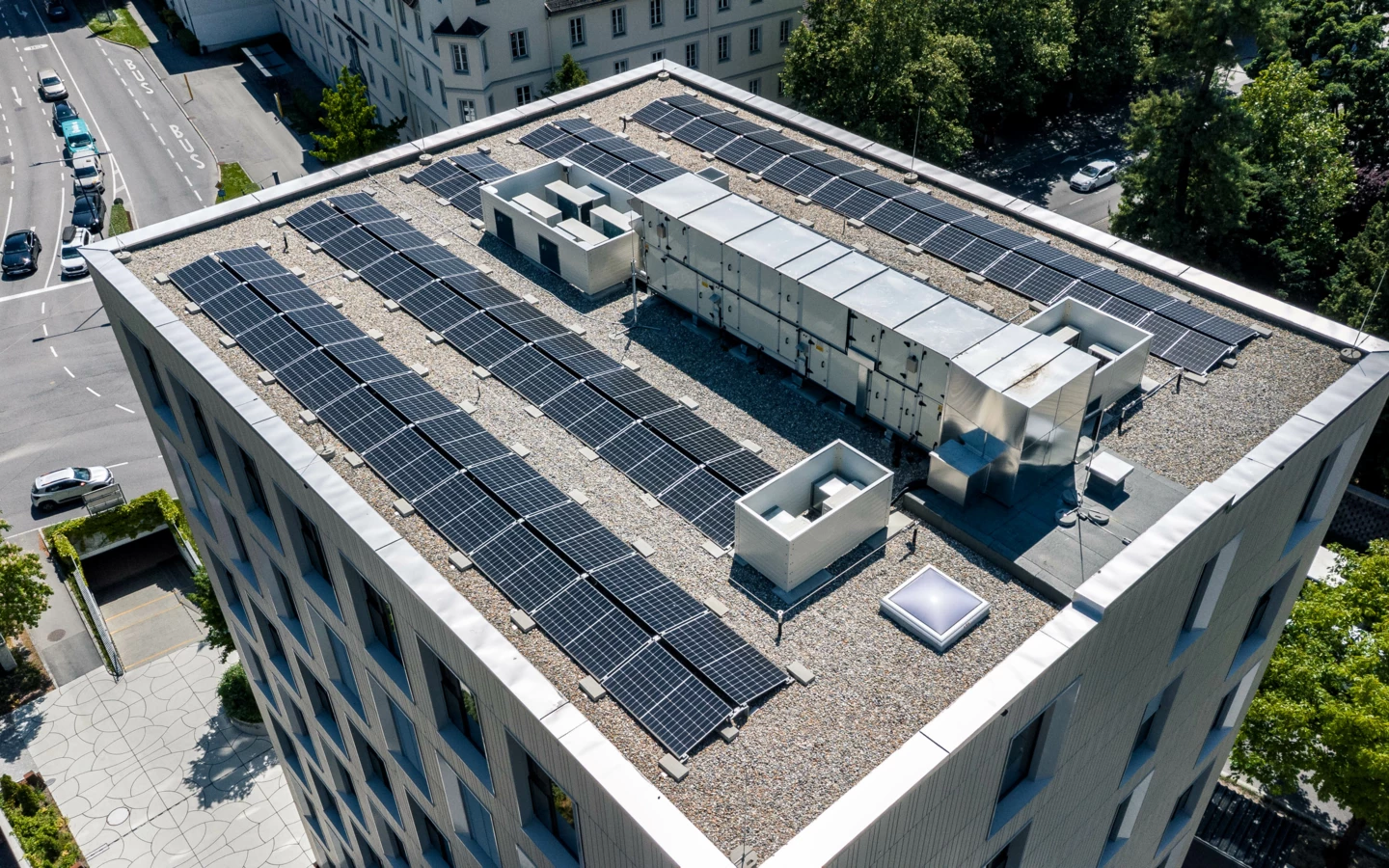 Aerial view of a contemporary building in Feldkirch with solar panels and HVAC units on its gravel rooftop (Baerahus).