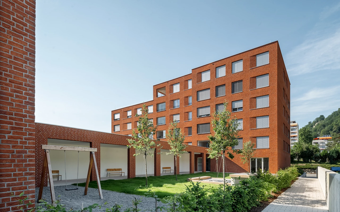 Wohngebäude mit Ziegelfassade, Spielplatz und Grünfläche davor (Seeblick, Lochau)