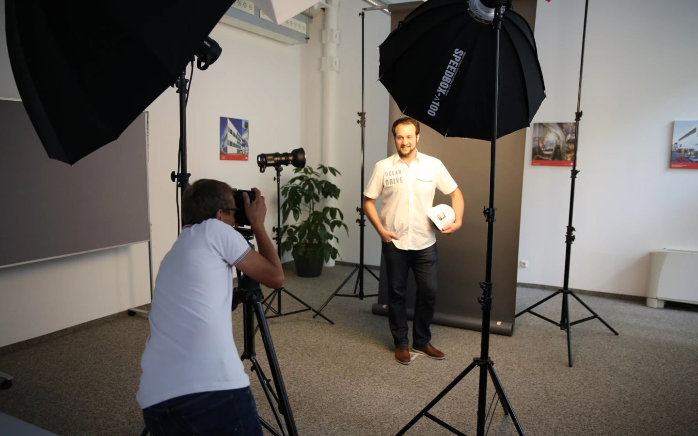 Ein professioneller Fotograf macht ein Porträtfoto eines Mannes mit Schutzhelm in einem Fotostudio mit Beleuchtungsausrüstung.