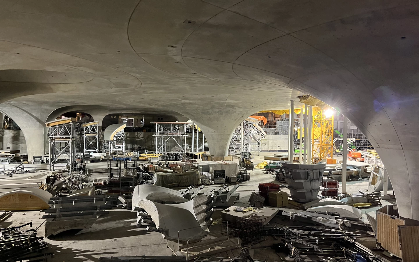 Eine große Baustelle mit gewölbten Betondecken, Baugerüsten und verschiedenen Baumaterialien. Kräne und Baugeräte sind im Hintergrund zu sehen (Rankweil, Deutschland).