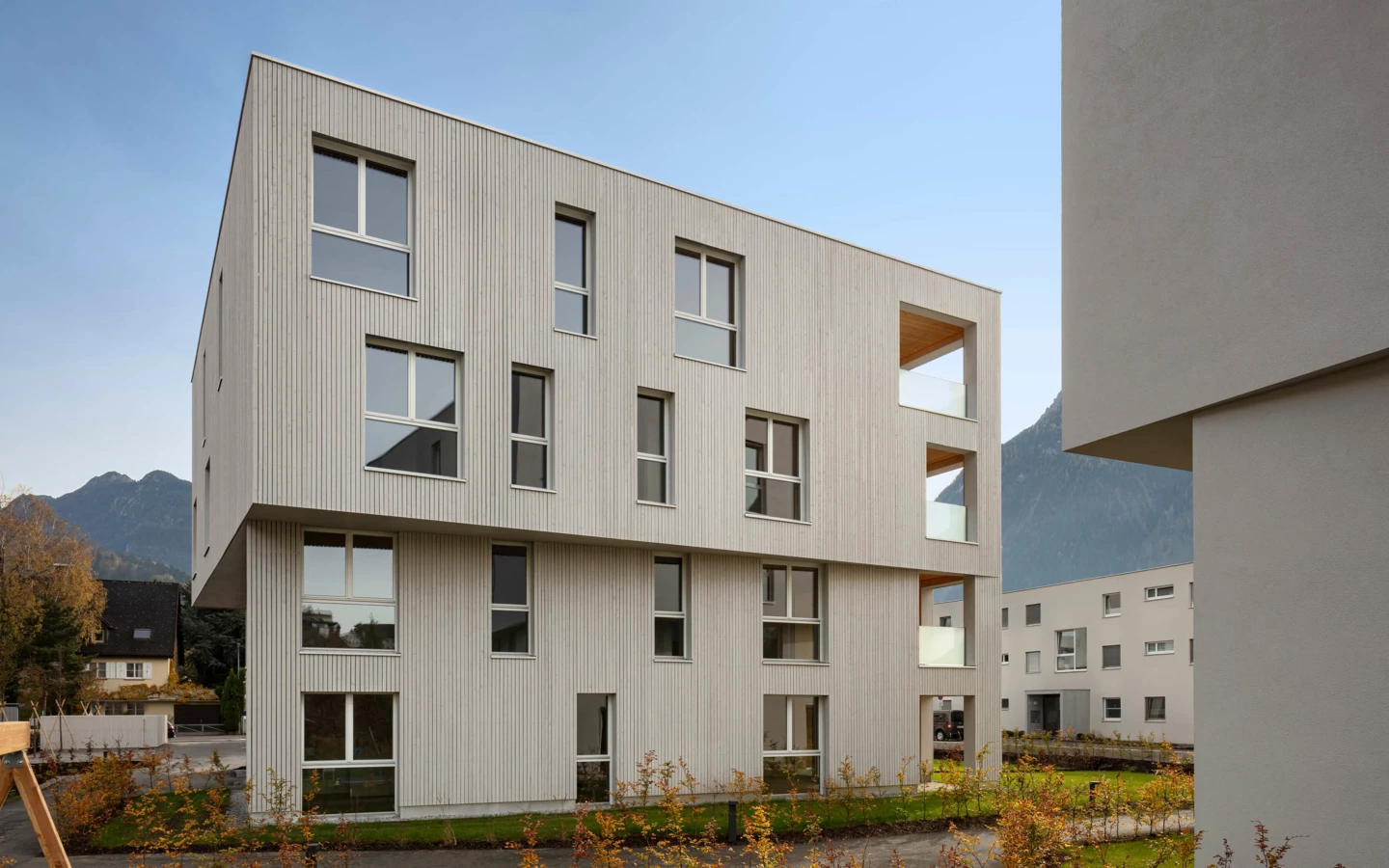 Moderne Wohnanlage Zürcherstrasse Bludenz mit Holzfassade und Balkonen, umgeben von jungem Grün und Bergen (Architektur)
