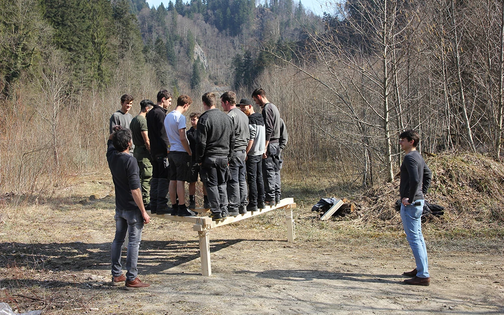 Eine Gruppe junger Männer balanciert auf einer Holzkonstruktion während des Lehrlingstages 2017 in der Natur.