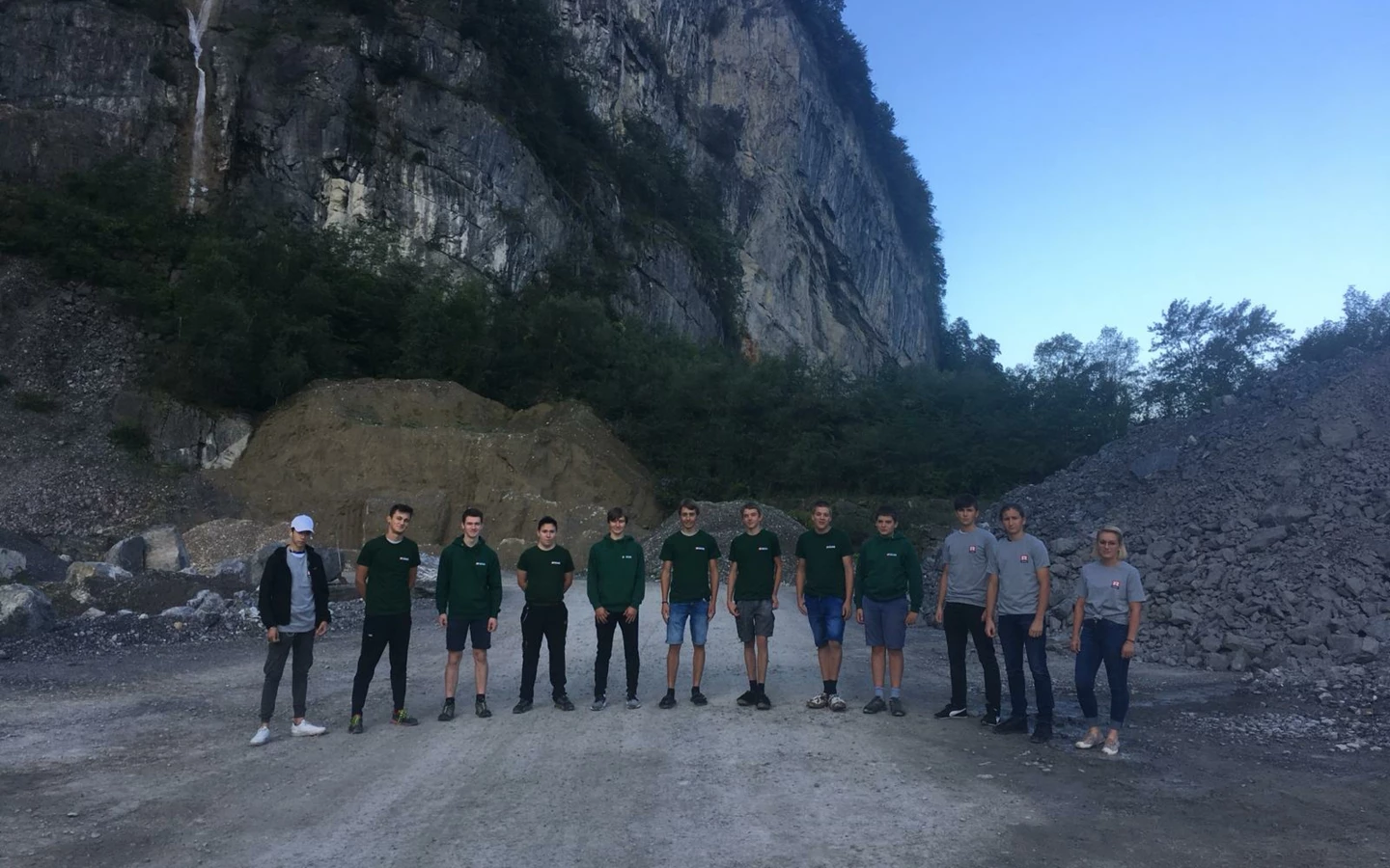 Eine Gruppe von 11 Auszubildenden des Lehrlingscamps 2019 posiert vor einer Felswand und Geröllhaufen.