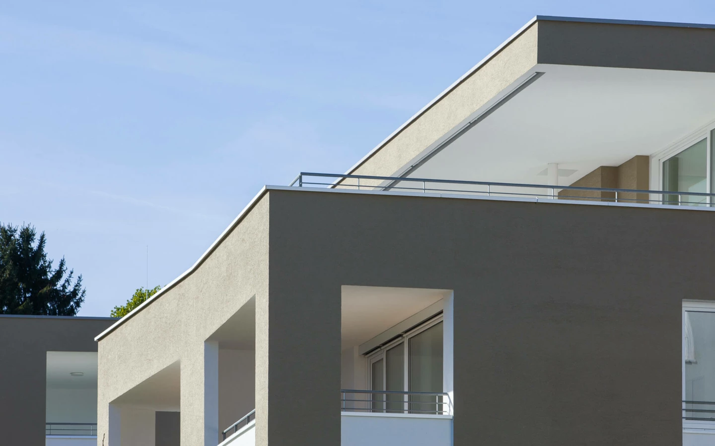 Moderne Wohnanlage Widum Lustenau mit Balkonen und Bäumen bei blauem Himmel