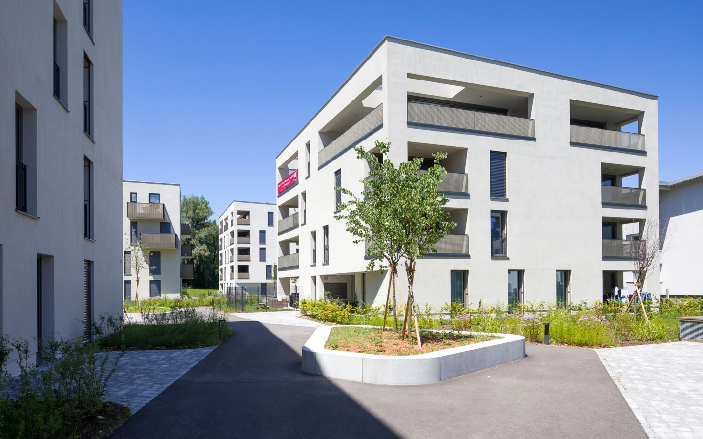 Moderne Wohnanlage 'Wohnen an der Furt' mit hellen Gebäuden, Balkonen und gepflegten Grünflächen unter blauem Himmel (Eigentumswohnung).