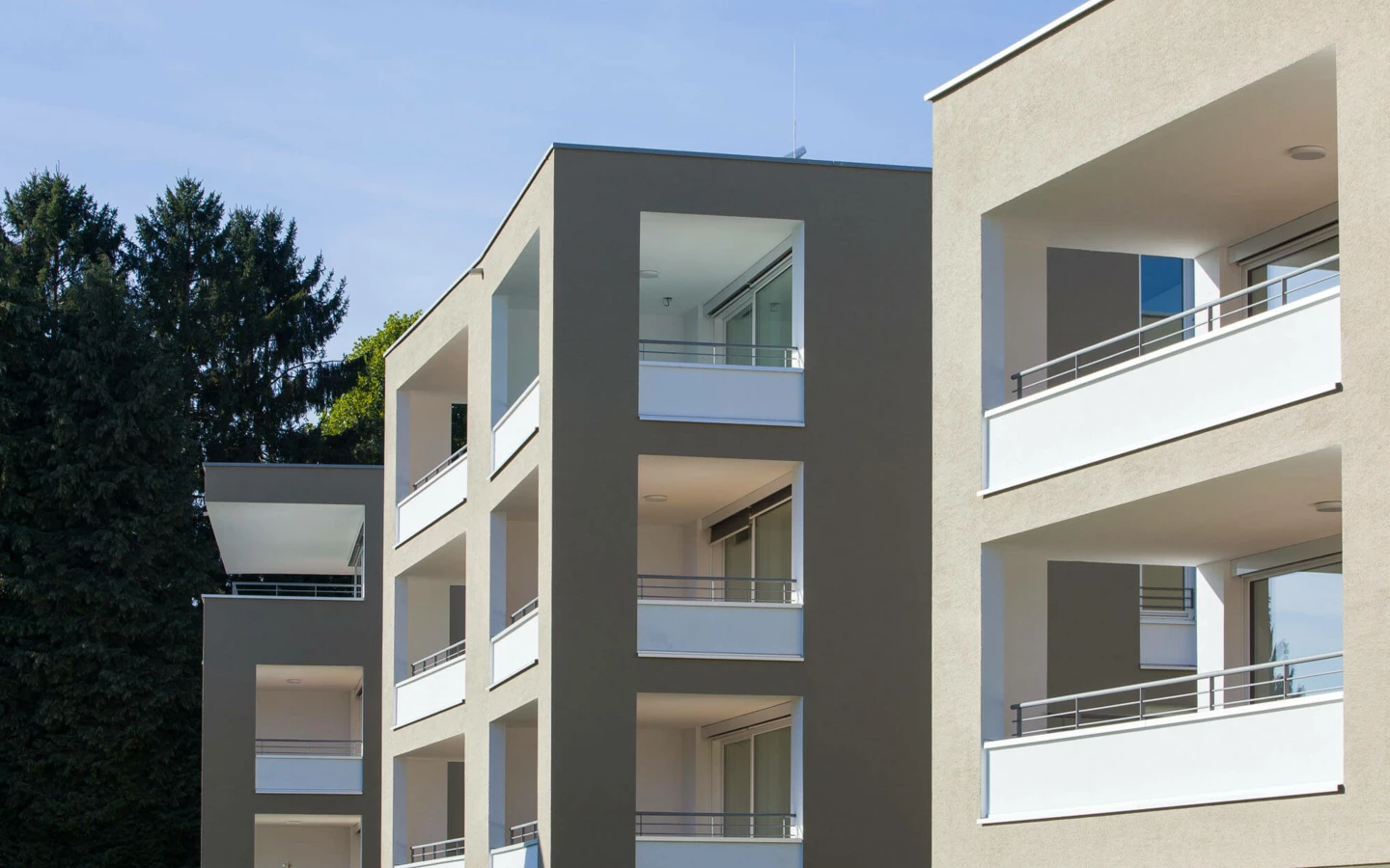 Moderne Wohngebäude mit beigen Fassaden und weißen Balkonen in der Wohnanlage Widum Lustenau.