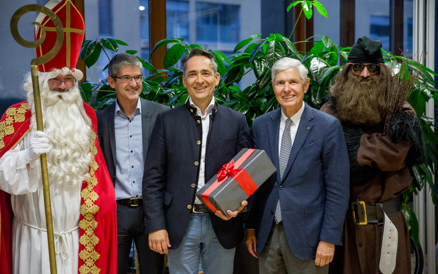 Fünf Männer posieren für ein Foto, zwei von ihnen sind als Nikolaus und Krampus verkleidet, inmitten von Pflanzen (Hubert, Geburtstag).