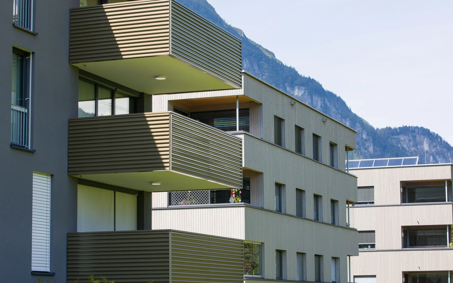 Moderne Wohnanlage in Vandans mit mehrstöckigen Gebäuden, Balkonen und Fenstern, im Hintergrund Berge (Bahnhofstraße, Bahnhofsstrasse).