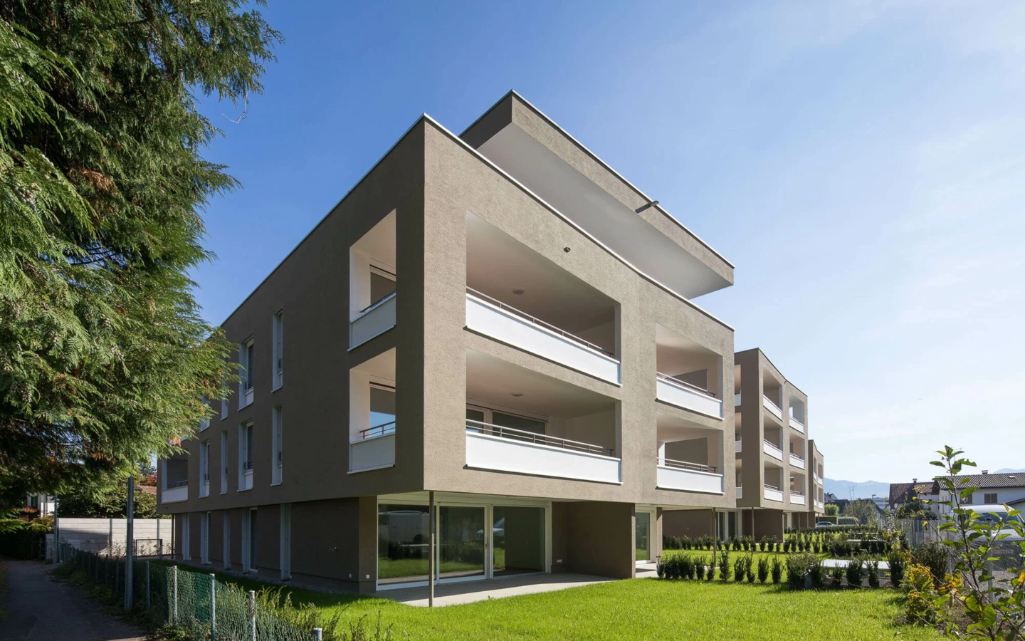 Wohnanlage Widum Lustenau 1 mit brauner Fassade und weißen Balkonen