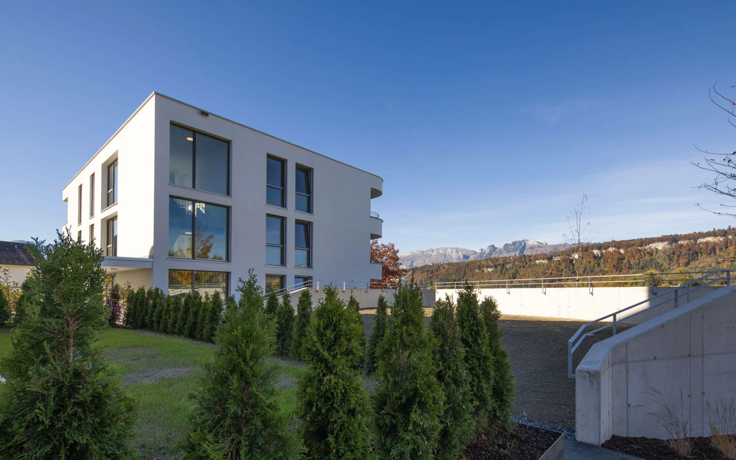 Moderne Wohnanlage Wolf-Huber-Straße Rundsicht auf ein weißes Gebäude und Berge bei Feldkirch.