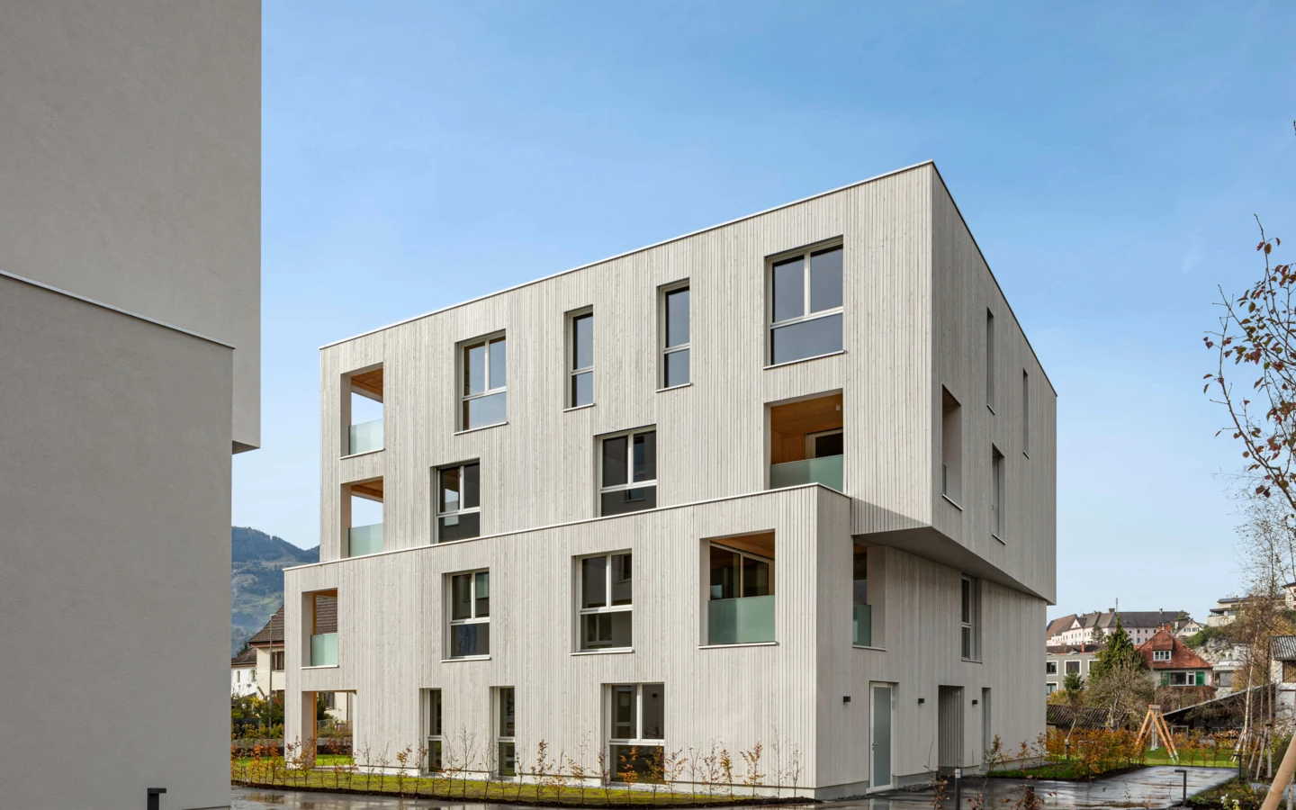 Modernes Mehrfamilienhaus mit heller Holzfassade und vielen Fenstern in Bludenz, umgeben von gepflegter Grünfläche (Zürcherstraße, Wohnanlage, Gebäude).