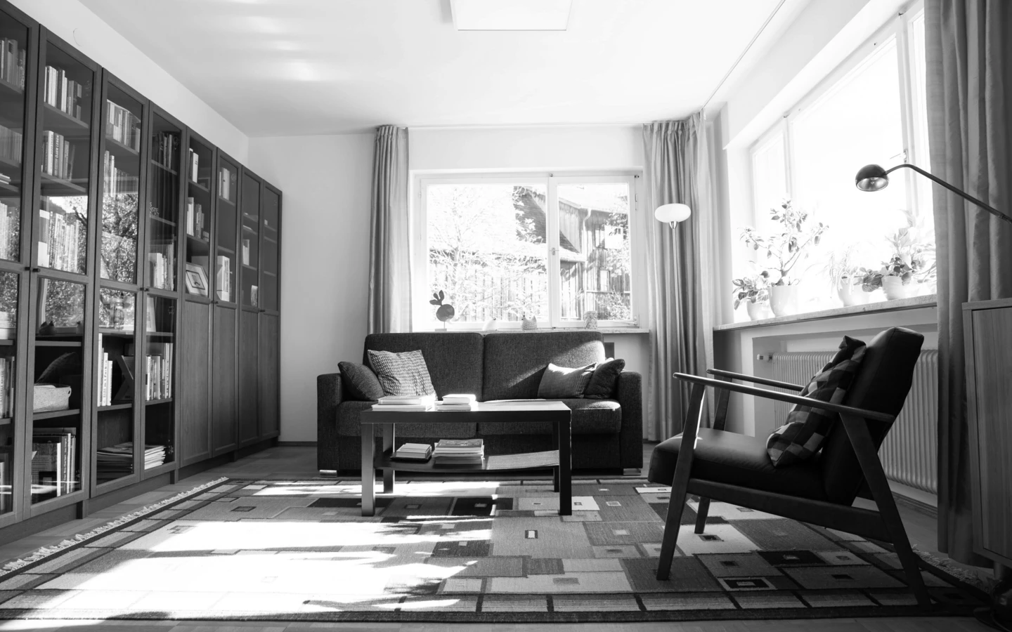 Wohnzimmer vor der Sanierung mit Sofa, Sessel, Teppich und Bücherregal in Dornbirn (Generalsanierung, Einfamilienhaus, Holzoptik).