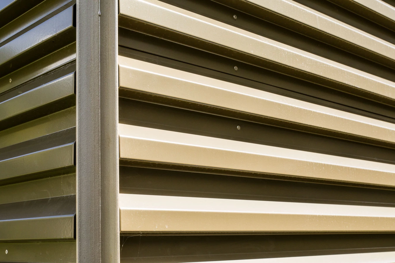 Detailaufnahme einer beigen Metallfassade mit horizontalen Lamellen und vertikalem Profil (Bahnhofstraße, Wohnanlage, Bahnhofsstrasse, Vandans).