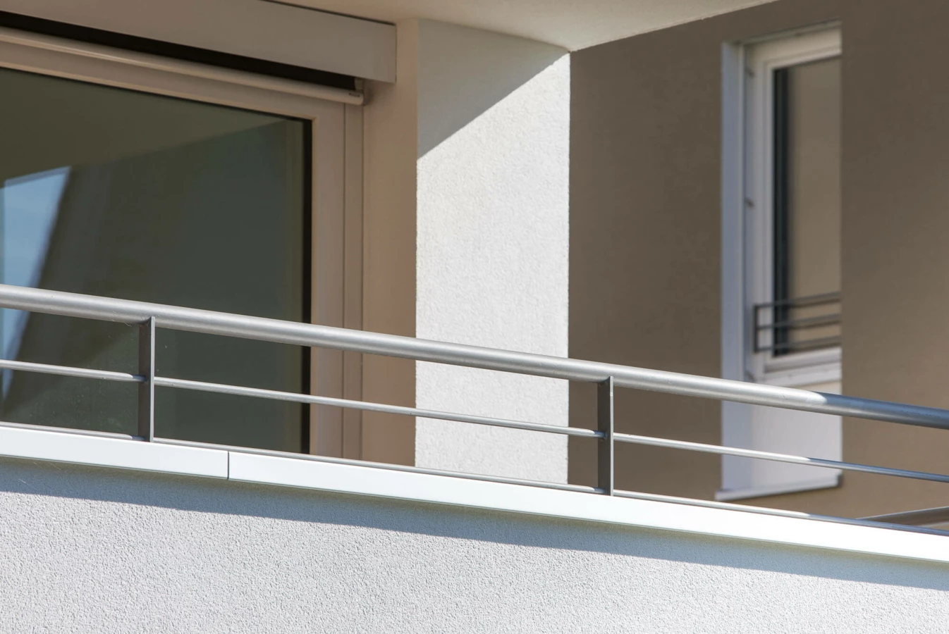 Balkon mit silbernem Geländer und Fenstern einer modernen Wohnanlage in Lustenau (Widum)