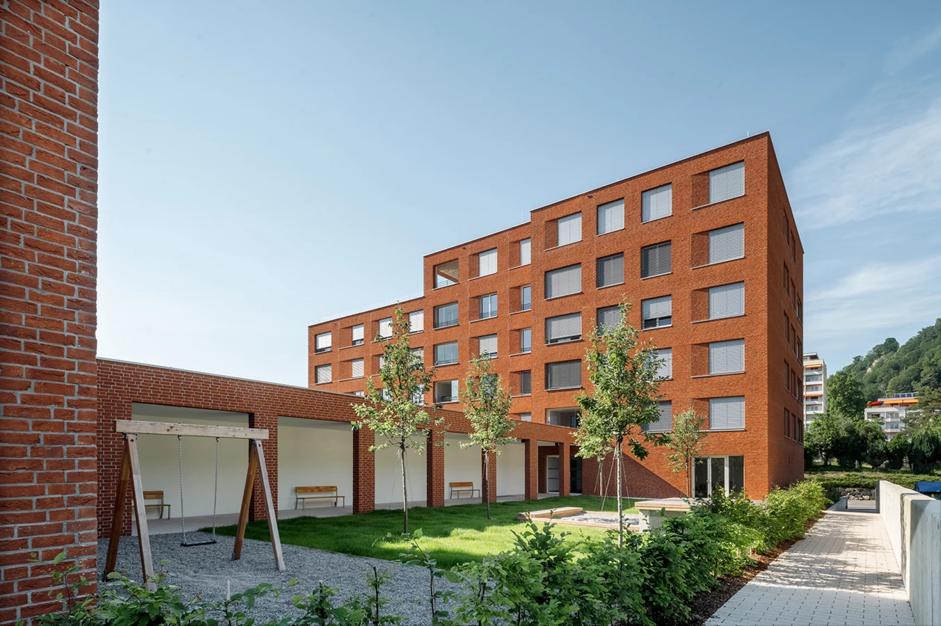 Wohngebäude mit Ziegelfassade, Spielplatz und Grünfläche davor (Seeblick, Lochau)
