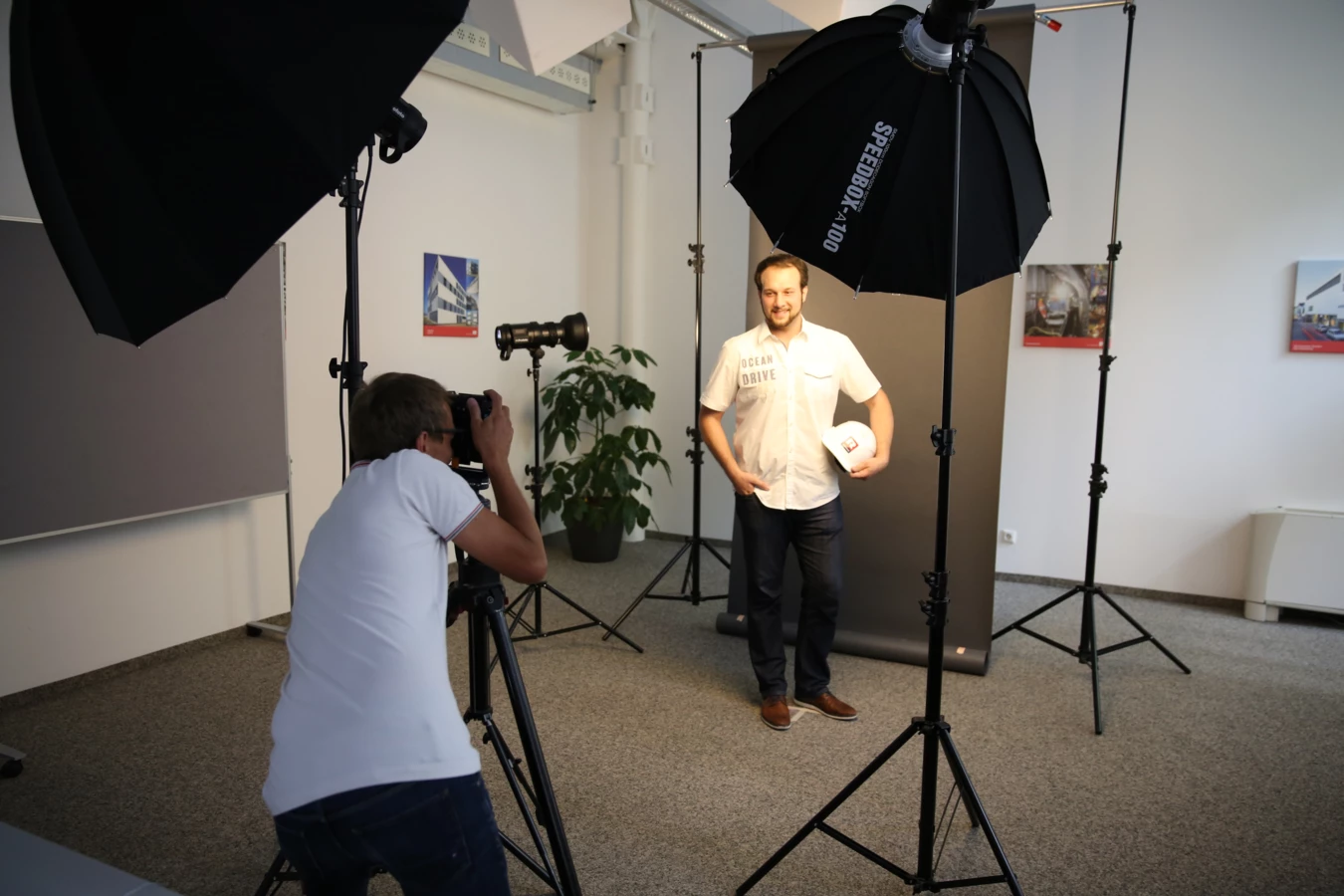 Ein professioneller Fotograf macht ein Porträtfoto eines Mannes mit Schutzhelm in einem Fotostudio mit Beleuchtungsausrüstung.