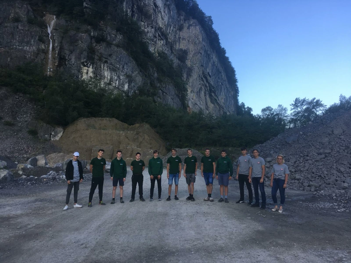 Eine Gruppe von 11 Auszubildenden des Lehrlingscamps 2019 posiert vor einer Felswand und Geröllhaufen.