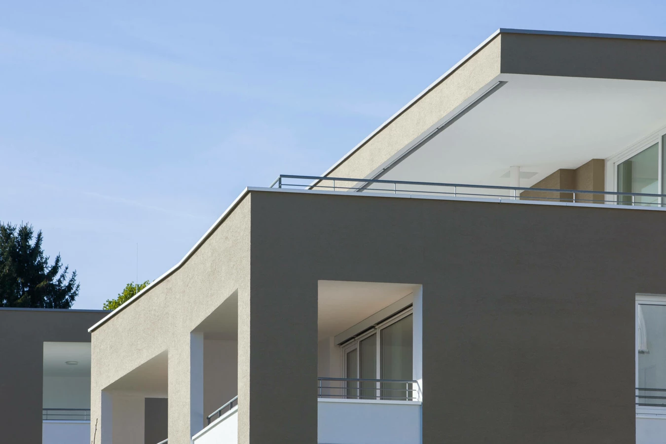 Moderne Wohnanlage Widum Lustenau mit Balkonen und Bäumen bei blauem Himmel