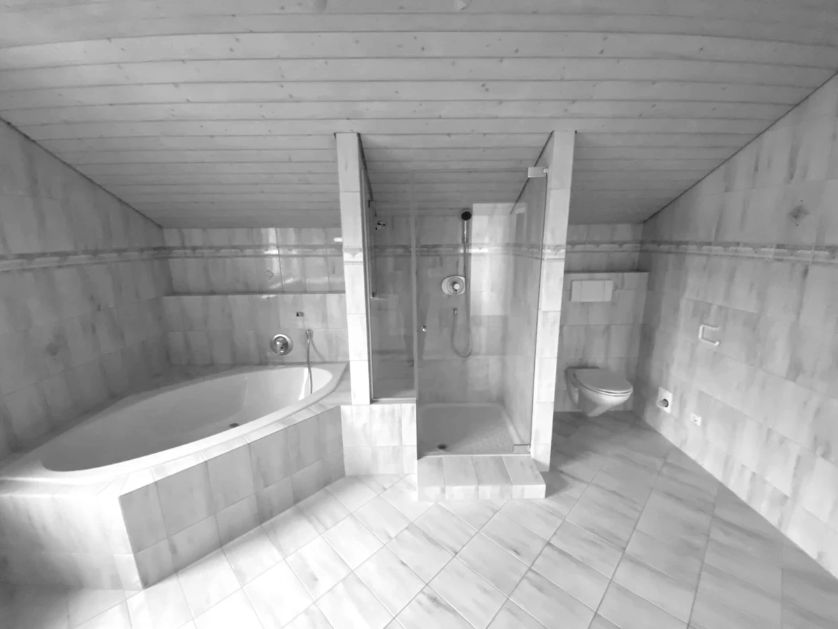 Badezimmer vor der Sanierung mit Badewanne, Dusche und Toilette in hellem Marmor-Look und Holzdecke (Generalsanierung, Bohle, Bad).