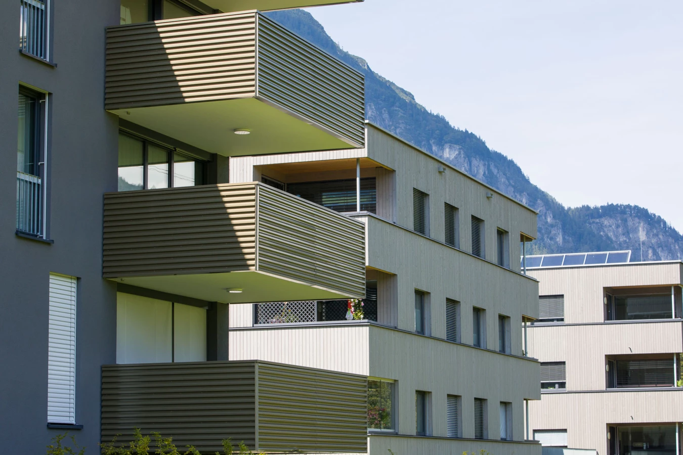 Moderne Wohnanlage in Vandans mit mehrstöckigen Gebäuden, Balkonen und Fenstern, im Hintergrund Berge (Bahnhofstraße, Bahnhofsstrasse).