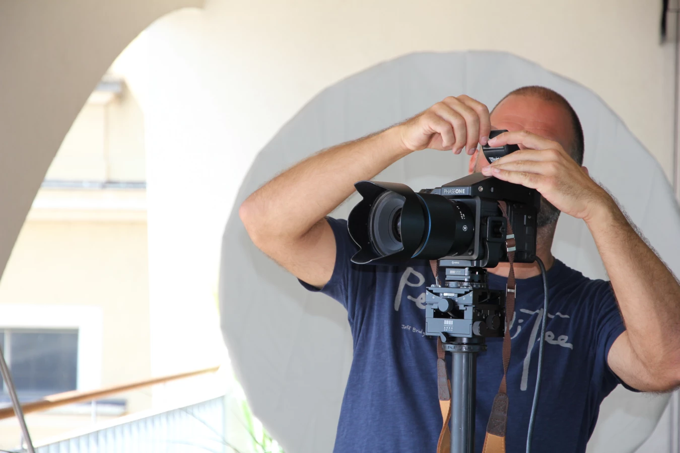 Ein Fotograf mit Glatze und Bart bedient eine professionelle Phase One-Kamera, die auf einem Stativ montiert ist.