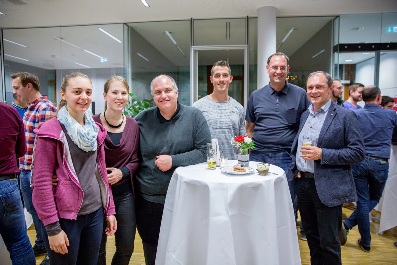 Eine Gruppe von Kollegen steht lächelnd an einem Stehtisch bei einer Veranstaltung von Rhomberg Bau (Hubert, Geburtstag).