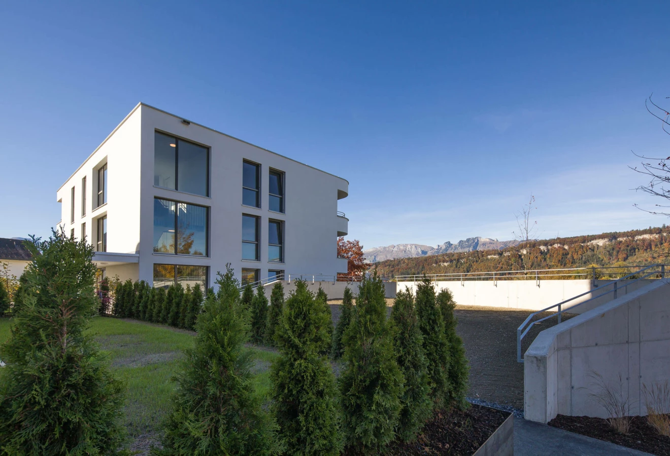 Moderne Wohnanlage Wolf-Huber-Straße Rundsicht auf ein weißes Gebäude und Berge bei Feldkirch.