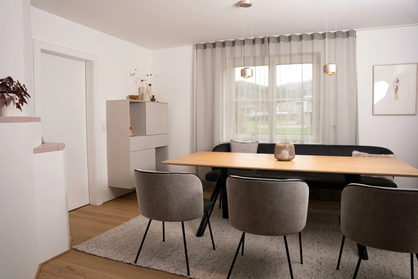 Modernes Esszimmer in einem Einfamilienhaus mit Holztisch, schwarzer Eckbank und grauen Stühlen. Helle Wandfarbe und ein Fenster lassen viel Licht herein (Generalsanierung, Bohle).